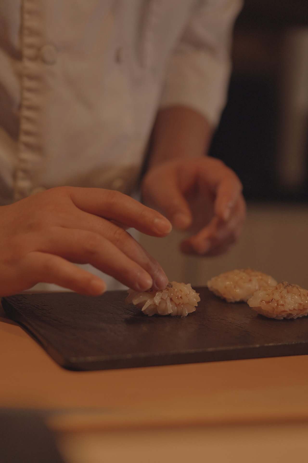 Chef brushing nikiri glaze on nigiri sushi