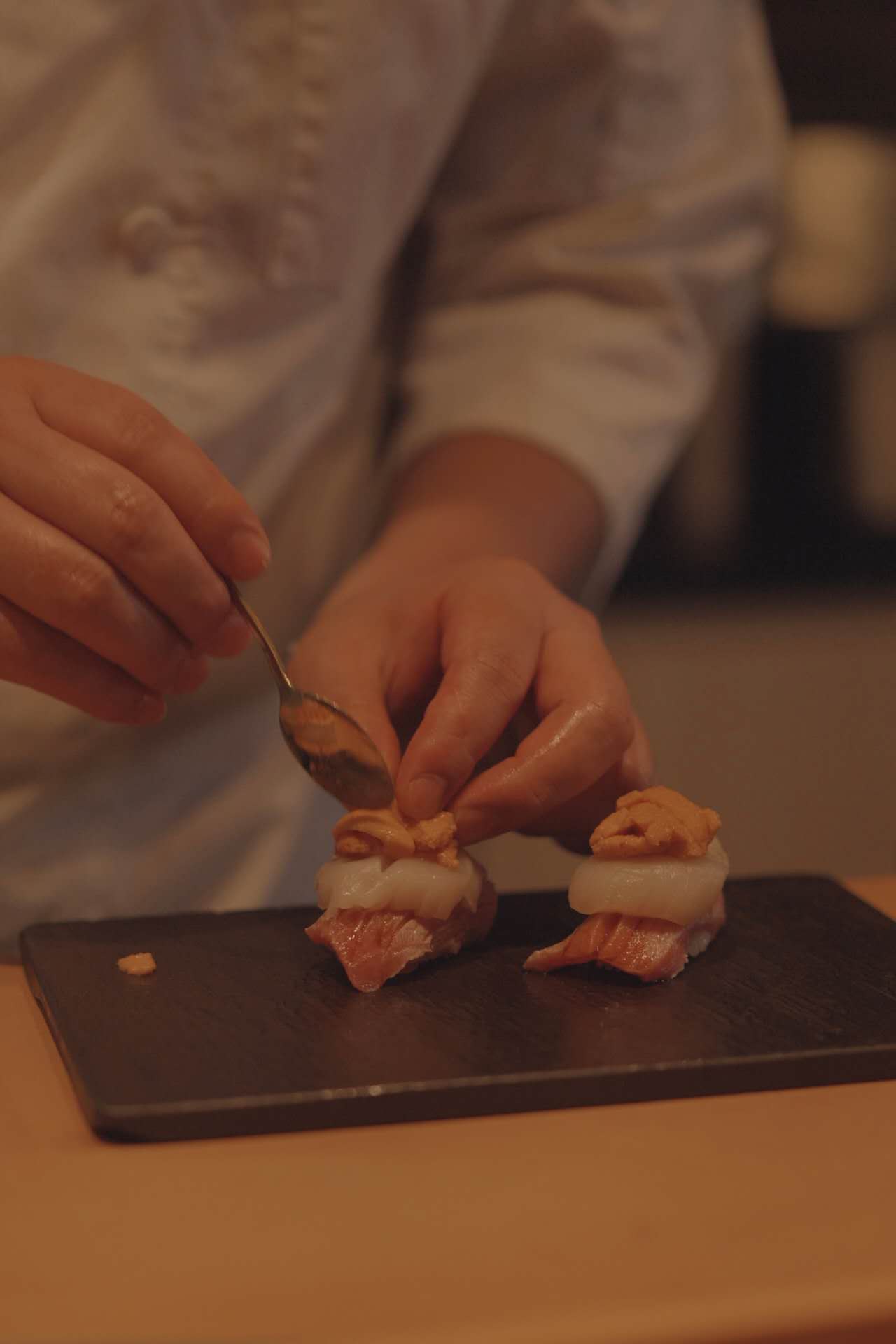 Chef plating uni nigiri at counter
